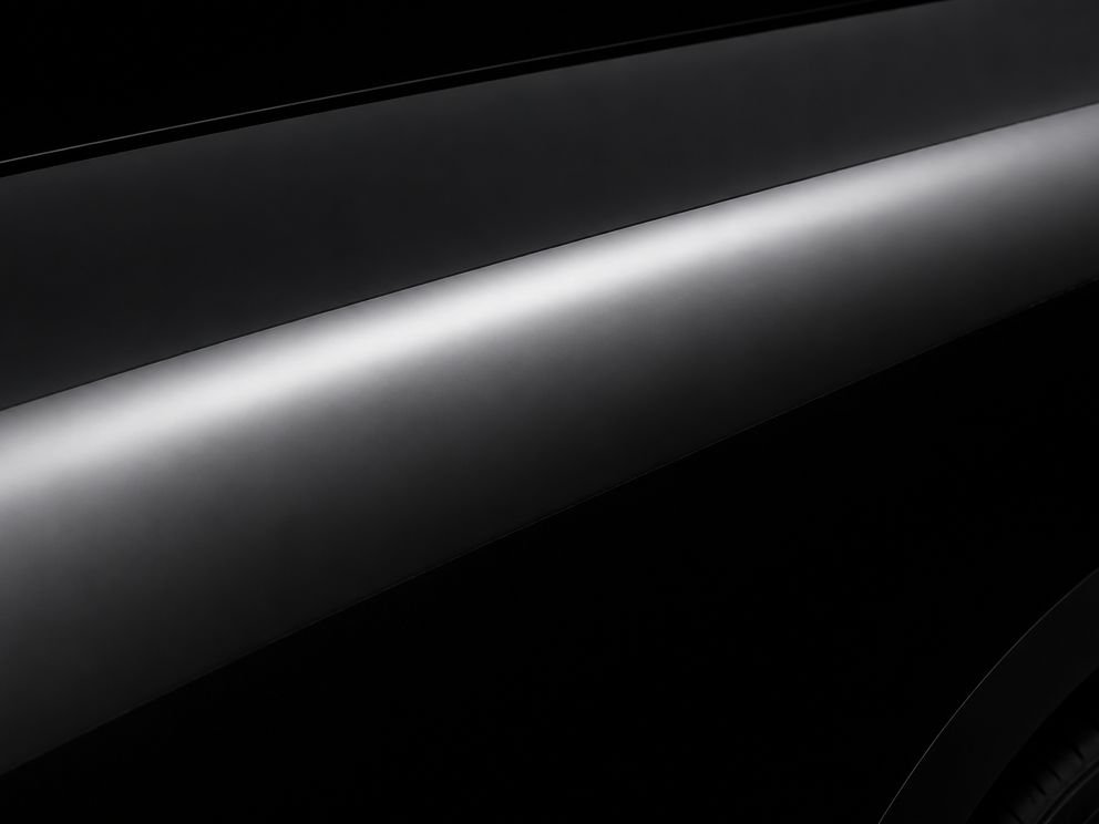A dark car panel in gloss black film, holding a hard clean reflection